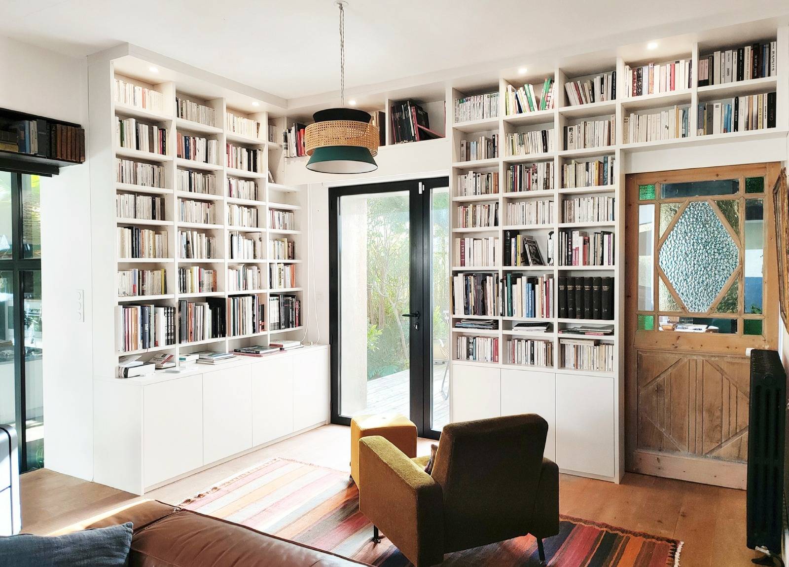 Grande bibliothèque en angle toute hauteur pour le coin lecture d'un séjour contemporain à Sanary sur Mer dans le Var. 